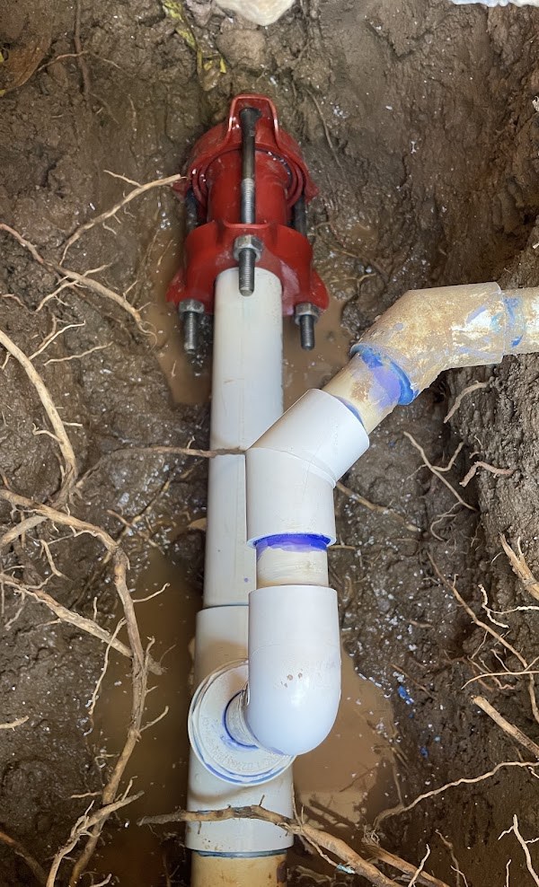 Sewer line repair with new PVC fittings in an excavated trench
