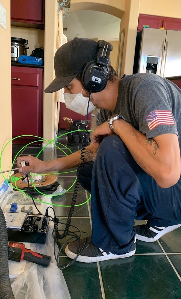 Technician performing acoustic slab leak detection in a kitchen