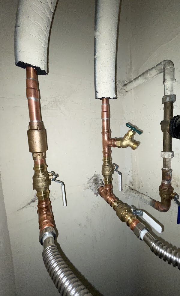 New copper supply lines and brass valves in a utility space
